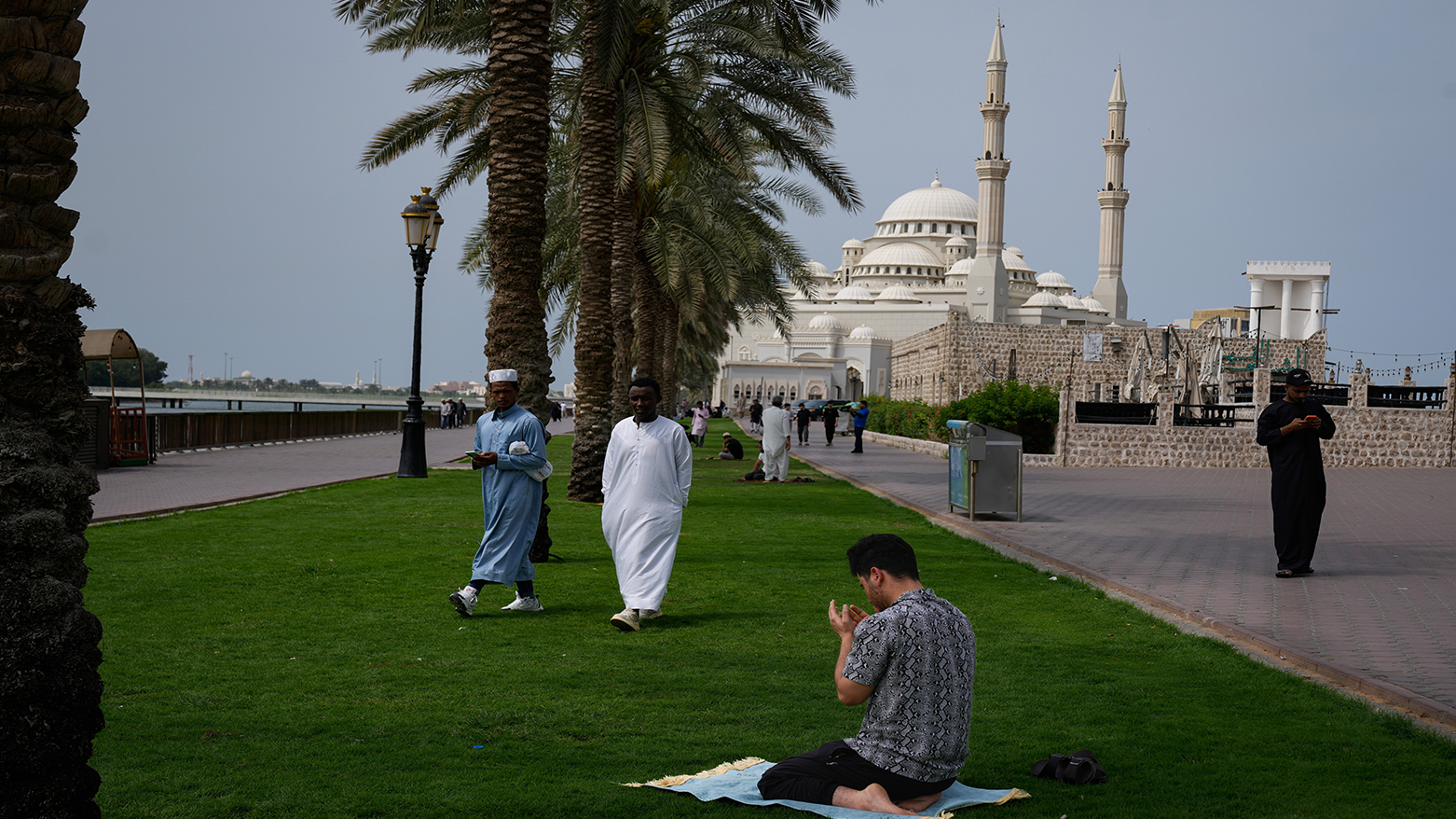 A Muslim man prays as others walk past him after attending the last Friday prayers of the holy fasting month of Ramadan outside Al Noor mosque in Sharjah, United Arab Emirates, March 13, 2026. (AP)