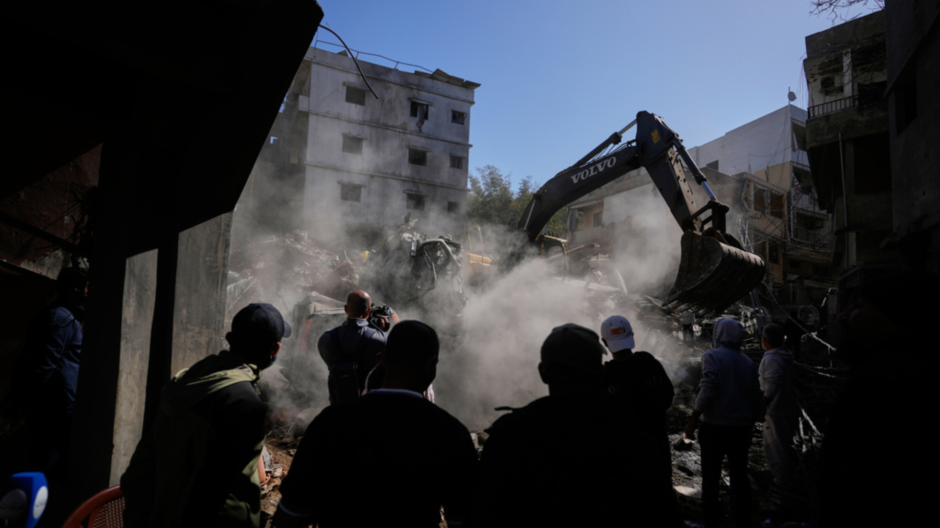 People gather as an excavator clears rubble at the site of Sunday's Israeli strike on a building in Beirut (Photo: AP)