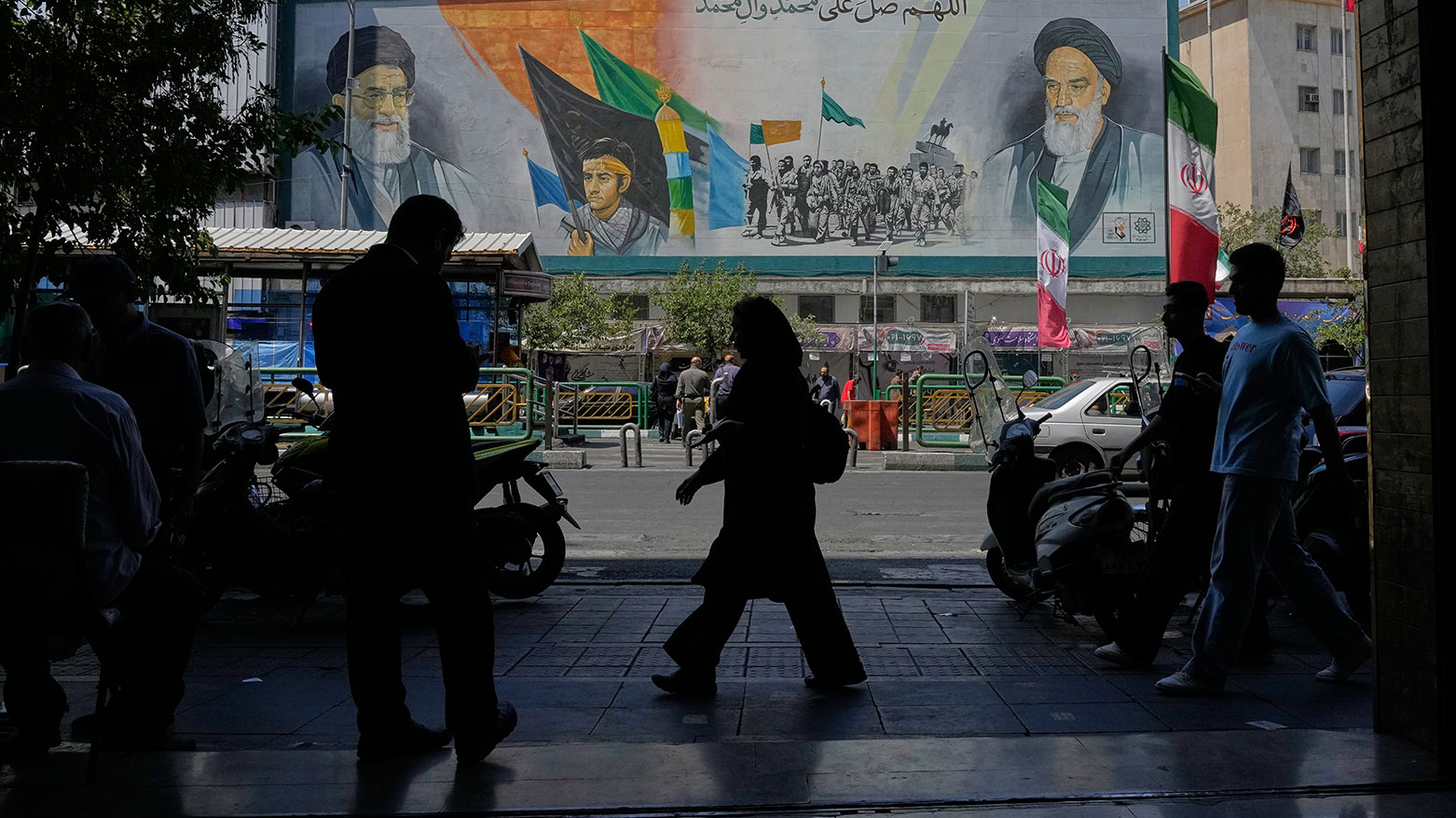 People walk past mural of Khomeini (R), slain leader Khamenei (L), Basij forces in Tehran, June 8, 2026. (Photo: AP)