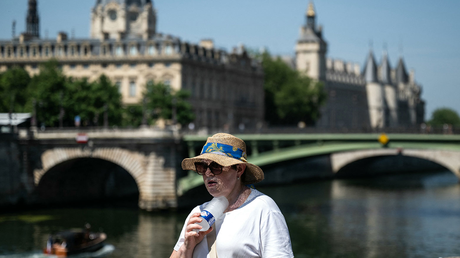 A woman with a hat cools off with a cold bottle of water on the Seine riverside, Paris, France, on June 21, 2026. (AFP)