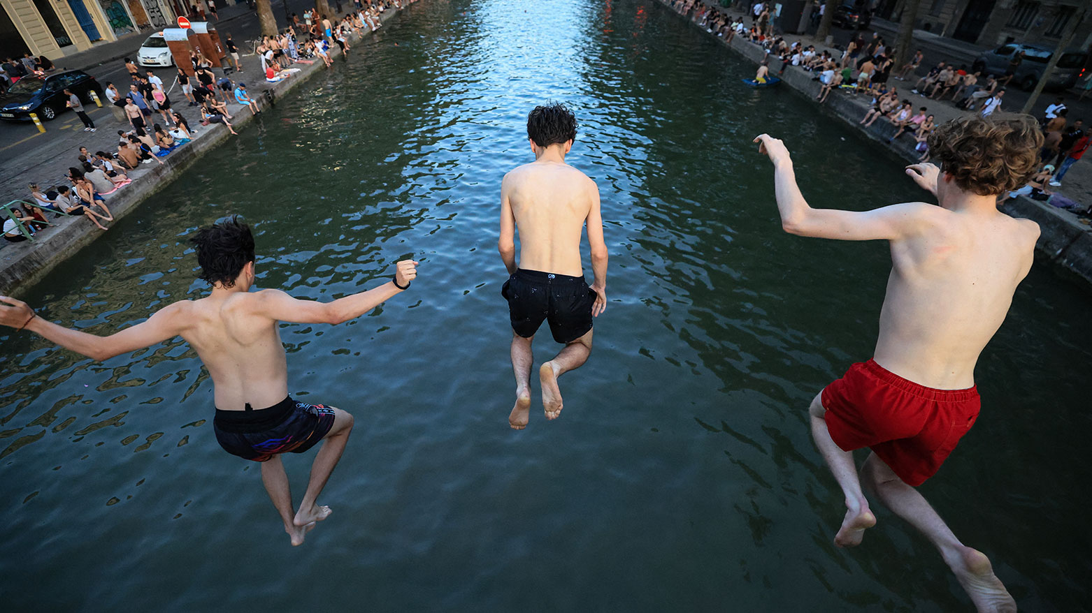 Youths jump from a bridge into the Canal Saint-Martin as France experiences a heatwave, in Paris on June 25, 2026. (AFP)