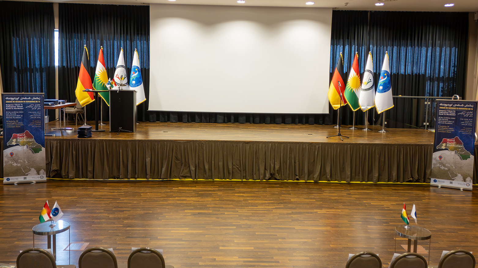 The stage of the International Kurdish Language Federation Congress, featuring from Left to Right, Germany’s flag, Kurdistan’s flag, KDC’s flag, and IKLF’s flag. (Photo: Sumar Al Hussein, Handed to Kurdistan24)