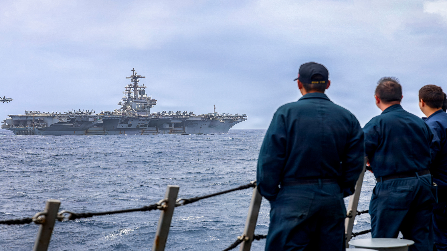 US Sailors assigned to destroyer USS Delbert D. Black, observing an F/A-18F Super Hornet, preparing to land on the flight deck of aircraft carrier USS George H.W. Bush, July 10, 2026. (CENTCOM)
