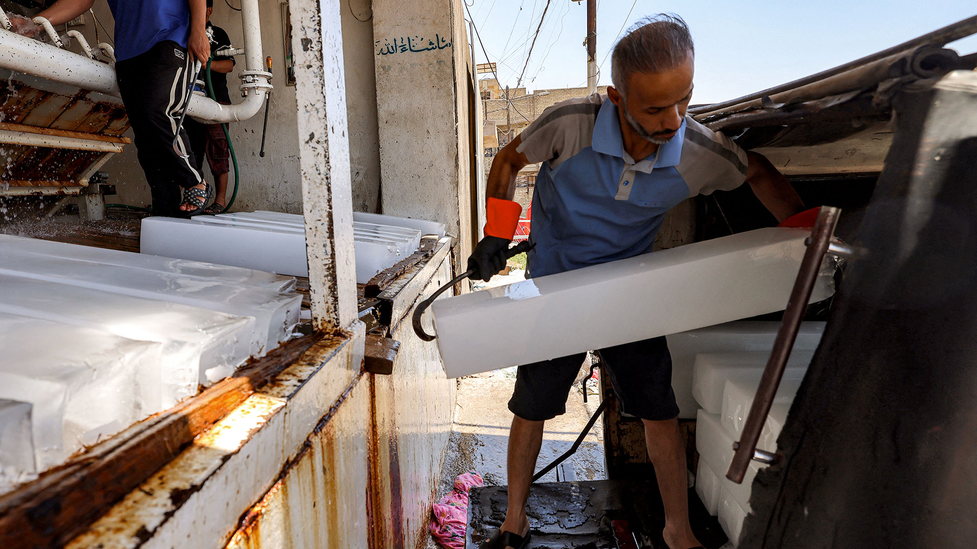 A worker loads freshly-made ice blocks from an ice-making factory onto a vehicle in Baghdad's eastern Sadr City suburb on July 27, 2026. (Photo: AFP)