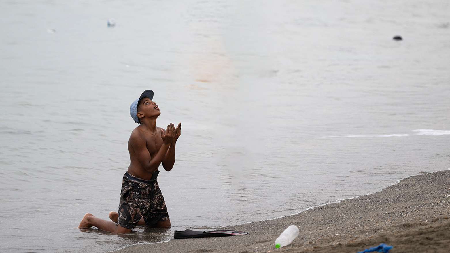 A migrant gestures on the beach around the border barrier with Morocco to enter Spain's north Africa's Ceuta enclave on July 31, 2026. (AFP)