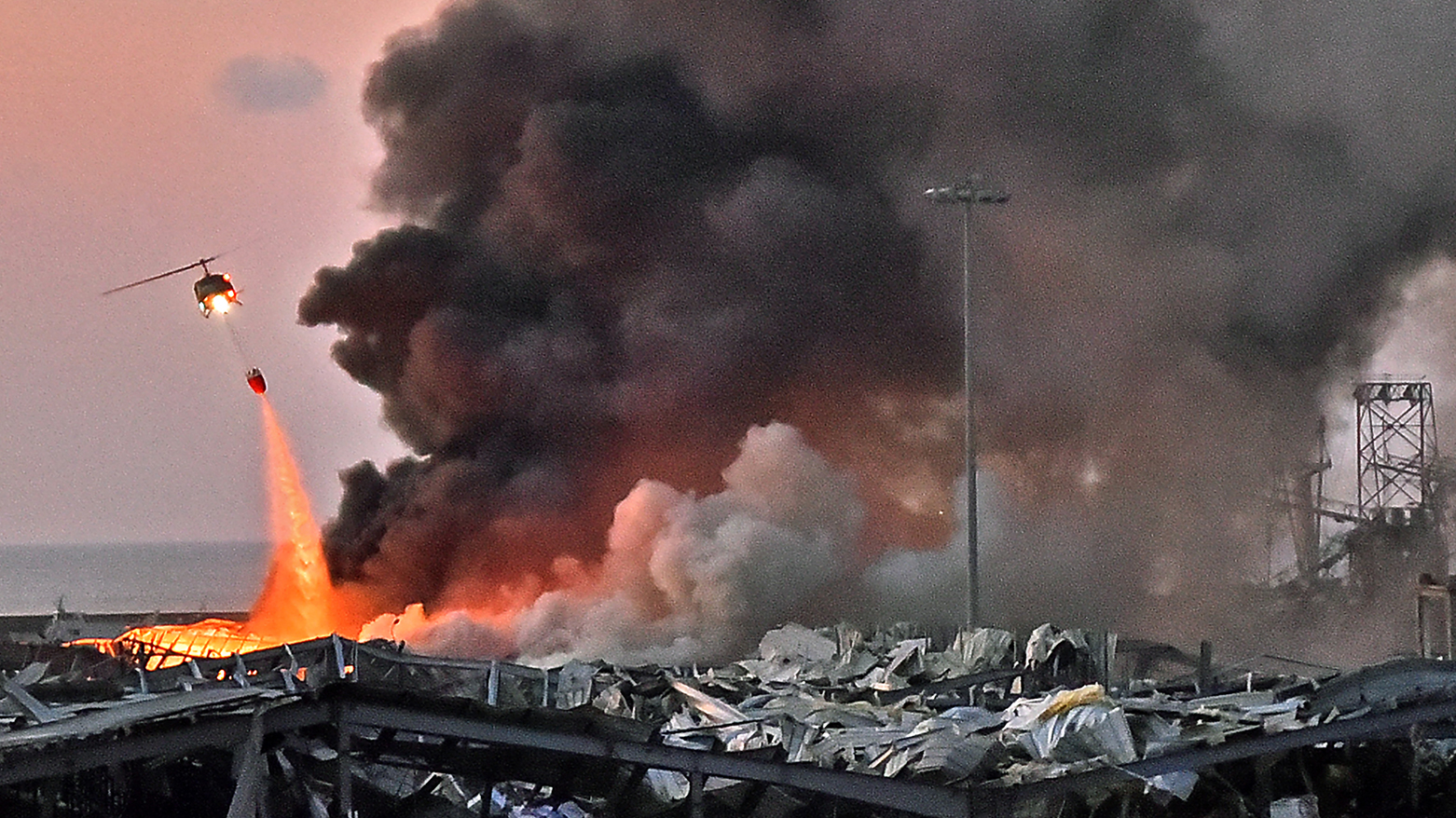 A helicopter puts out a fire at the scene of an explosion at the port of Lebanon's capital Beirut on August 4, 2020. (AFP)