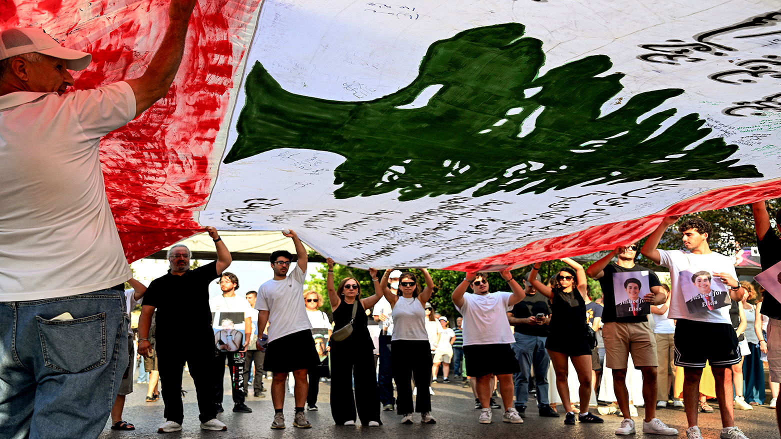 Family members of the 2020 victims Beirut port explosion march with a giant Lebanese flag on the 6th anniversary of the incident near the port area in Beirut on Aug. 4, 2026. (AFP)
