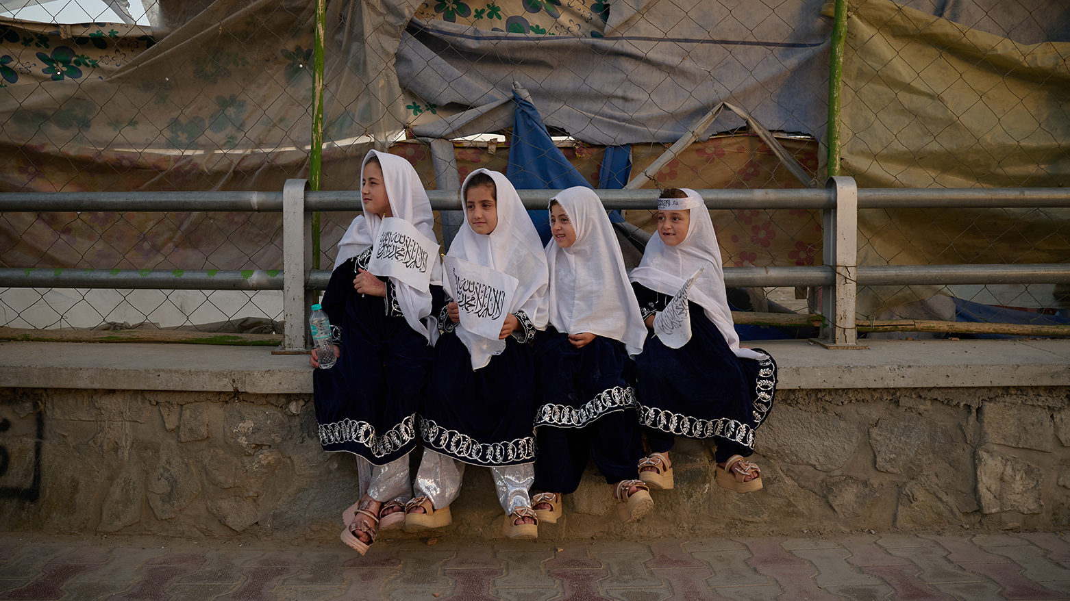 Four young girls dressed in matching outfits hold Taliban flags on the eve of the fifth anniversary of the U.S. withdrawal and the start of Taliban rule in Kabul, Afghanistan, Friday, Aug. 14, 2026. (AP Photo/Nava Jamshidi)