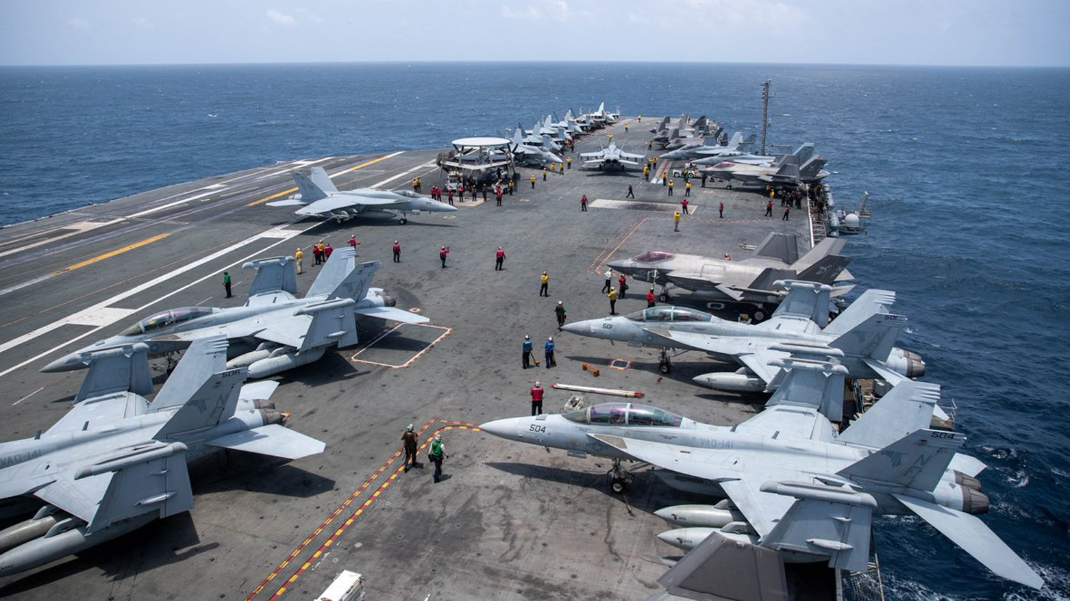 U.S. Navy sailors conducting flight deck operations aboard the aircraft carrier USS George Washington (CVN 73) while transiting the Arabian Sea, surrounded by parked EA-18G Growler, F/A-18 Super Hornet, and F-35C Lightning II aircraft. (CENTCOM)
