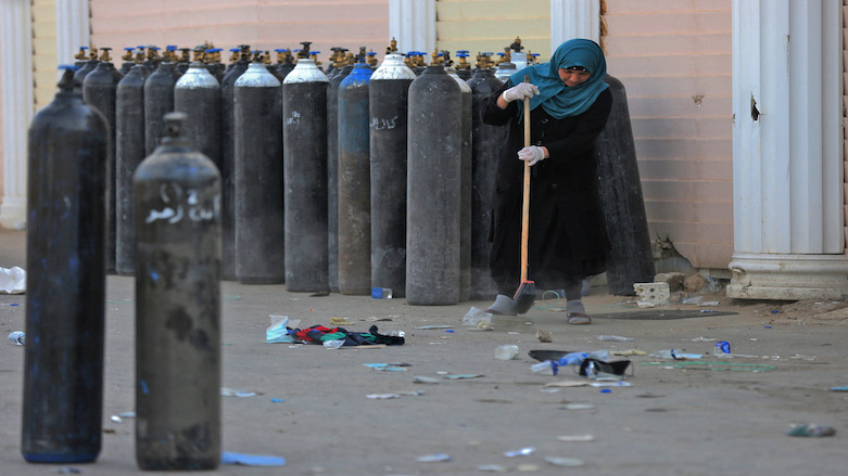 An Iraqi woman cleans debris next to oxygen bottles outdoors at the Ibn Al-Khatib Hospital in Baghdad, on April 25, 2021, after a fire erupted in the medical facility reserved for the most severe COVID-19 cases. (Photo: Ahmad Al-Rubaye/AFP)