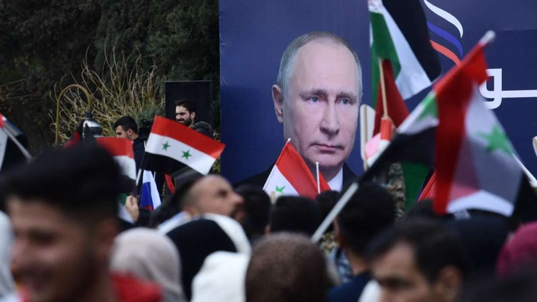 Syrian students wave the Syrian, Russian and Palestinian flags under a billboard bearing the portrait of Russian President Vladimir Putin during a demonstration in support of Russia, March 10, 2022. (Photo: AFP)