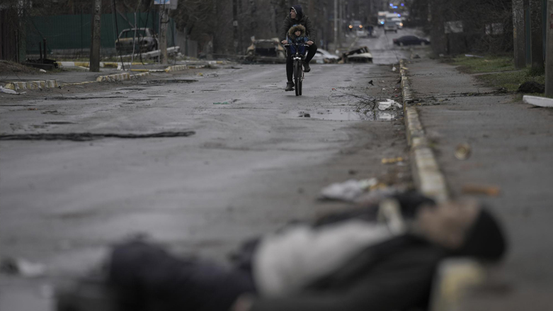 A man and child on a bicycle come across the body of a civilian lying on a street in the formerly Russian-occupied Kyiv suburb of Bucha, Ukraine, April 2, 2022. (Photo: Vadim Ghirda/AP)