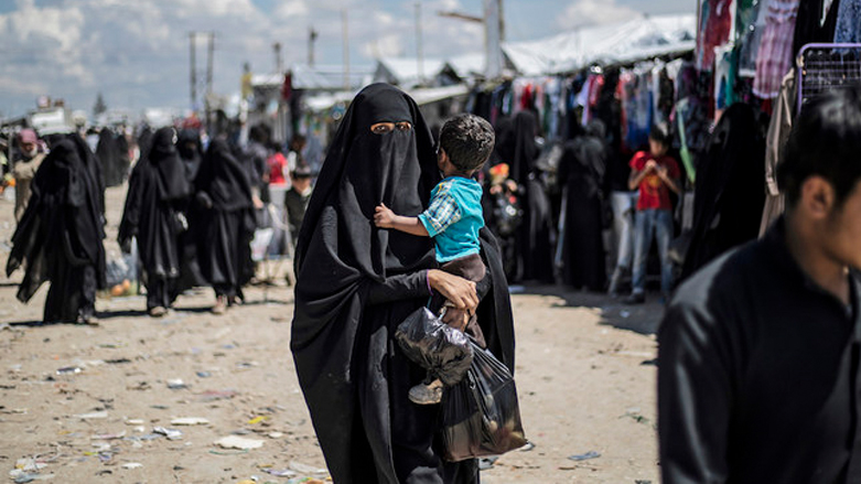 A veiled woman carries a toddler in northeastern Syria's Al-Hol Camp. (Photo: Delil Souleiman/AFP)
