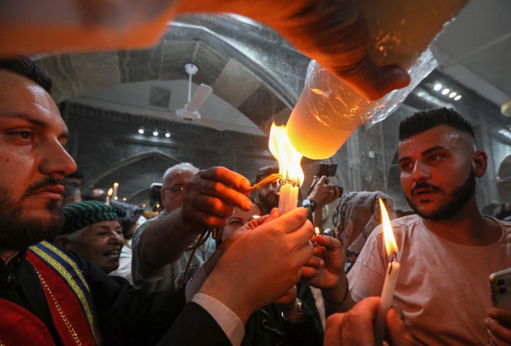 Iraqi Orthodox Christians celebrating Easter Saturday share the flame of the Holy Fire brought from Jerusalem, at the church of the ancient Mar Matta monastery of Saint Matthew, in the village of Bashiqa, April 23, 2022. (Photo: Safin Hamed/AFP)