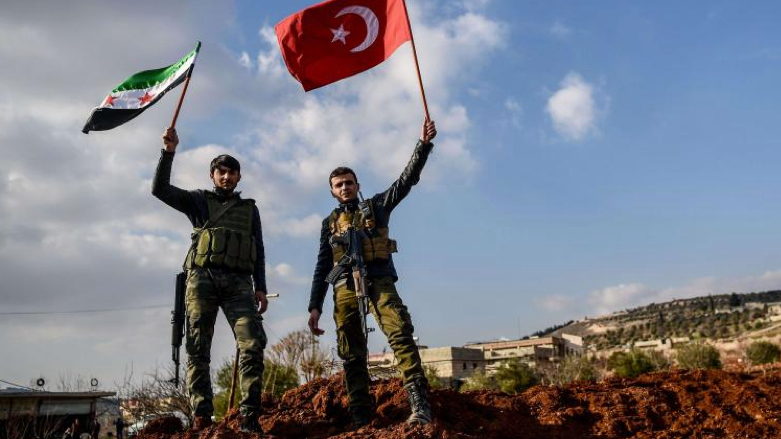 Turkish-backed Syrian rebel fighters hold a Turkish national flag and a Free Syrian Army flag at a checkpoint in Azaz on a road leading to Afrin (Photo: AFP)