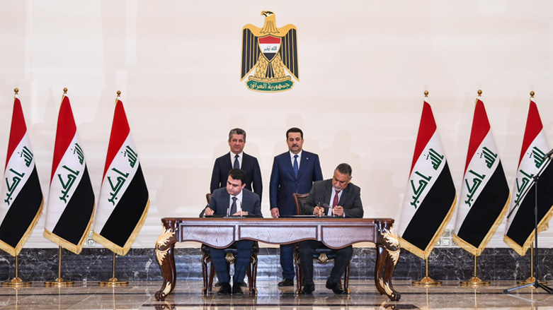 Kurdistan Region Prime Minister Masrour Barzani (standing/left) is pictured next to Iraqi Prime Minister Mohammed Shia' Al-Sudani (standing/right) as Kurdish and Iraqi officials sign a deal to resume oil export, April 4, 2023. (Photo: KRG)