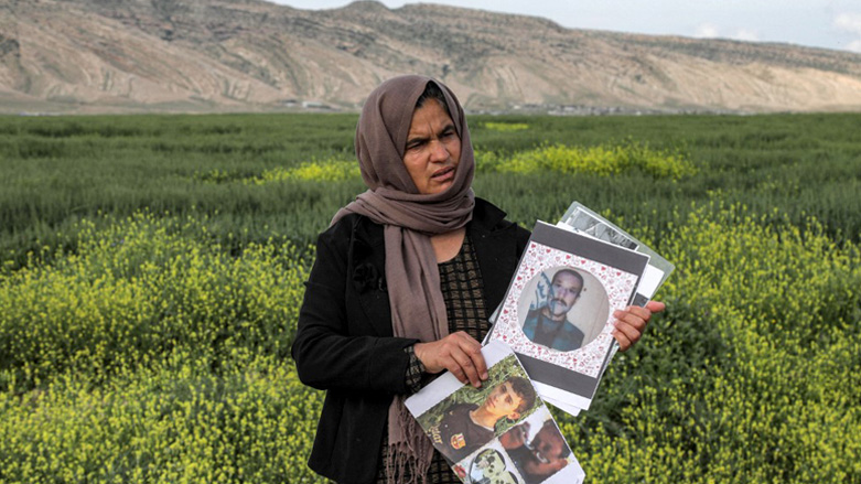 Bahar Elias, a 40-year-old displaced Iraqi woman from the Yazidi community, poses for a picture while holding photos of other family members kidnapped by the Islamic State (IS) group, April 19, 2023. (Photo: Safin Hamed/AFP)