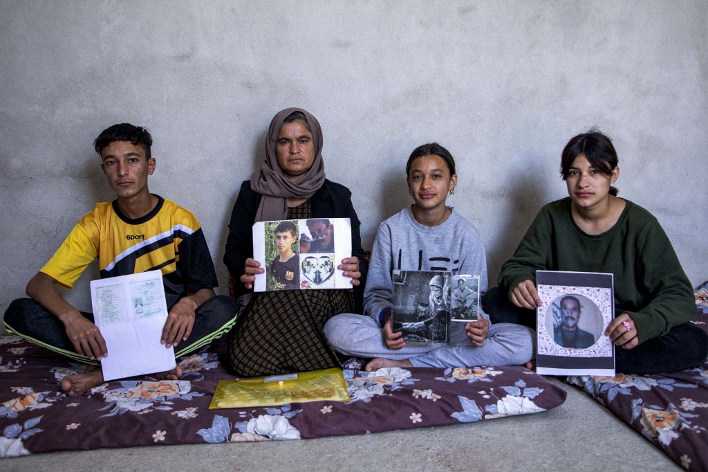 Bahar Elias, a 40-year-old displaced Iraqi woman from the Yazidi community, poses for a picture with her son and daughters while holding pictures of other family members kidnapped by the Islamic State (IS), April 22, 2023. (Photo: Safin Hamed/AFP)