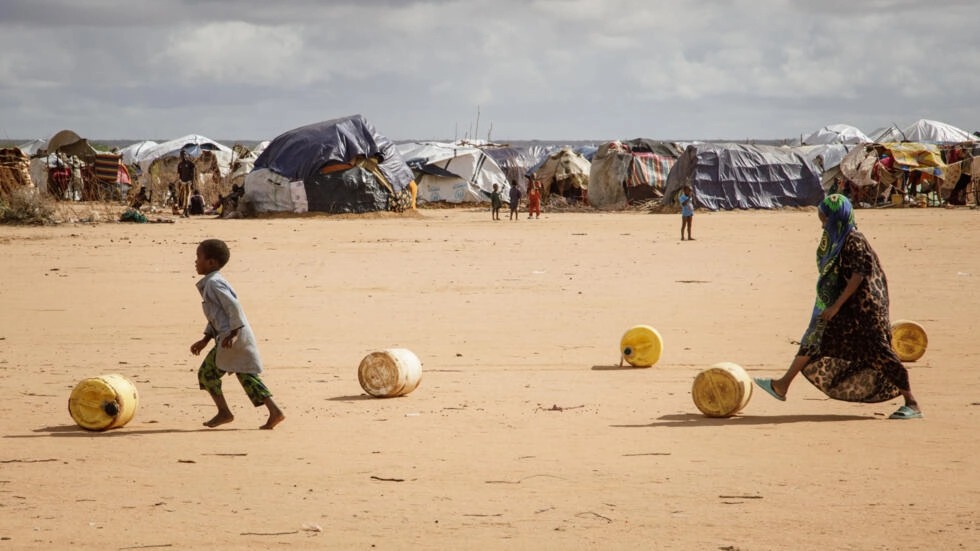 أطفال صوماليون يلفون حاويات مياه يعيدونها إلى مأواهم المؤقت في مخيم داداب للاجئين في كينيا في 23 آذار/مارس 2023 © بوب موريتي / ا ف ب