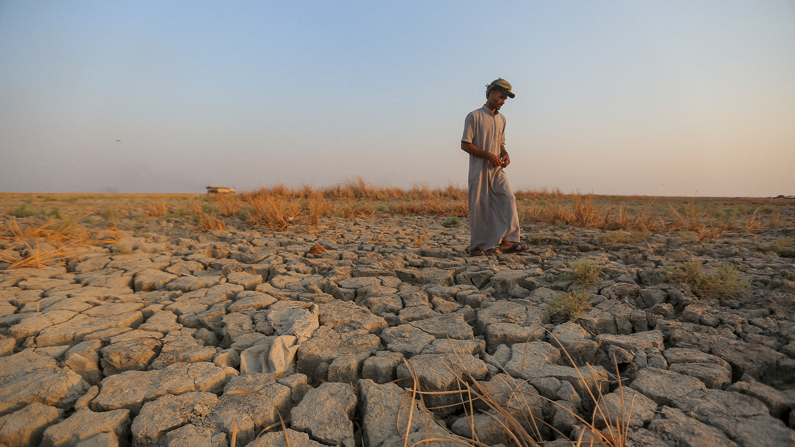 A fisherman walks across a dry patch of land in the marshes in Dhi Qar province, Iraq, Sept. 2, 2022. (Photo: AP)