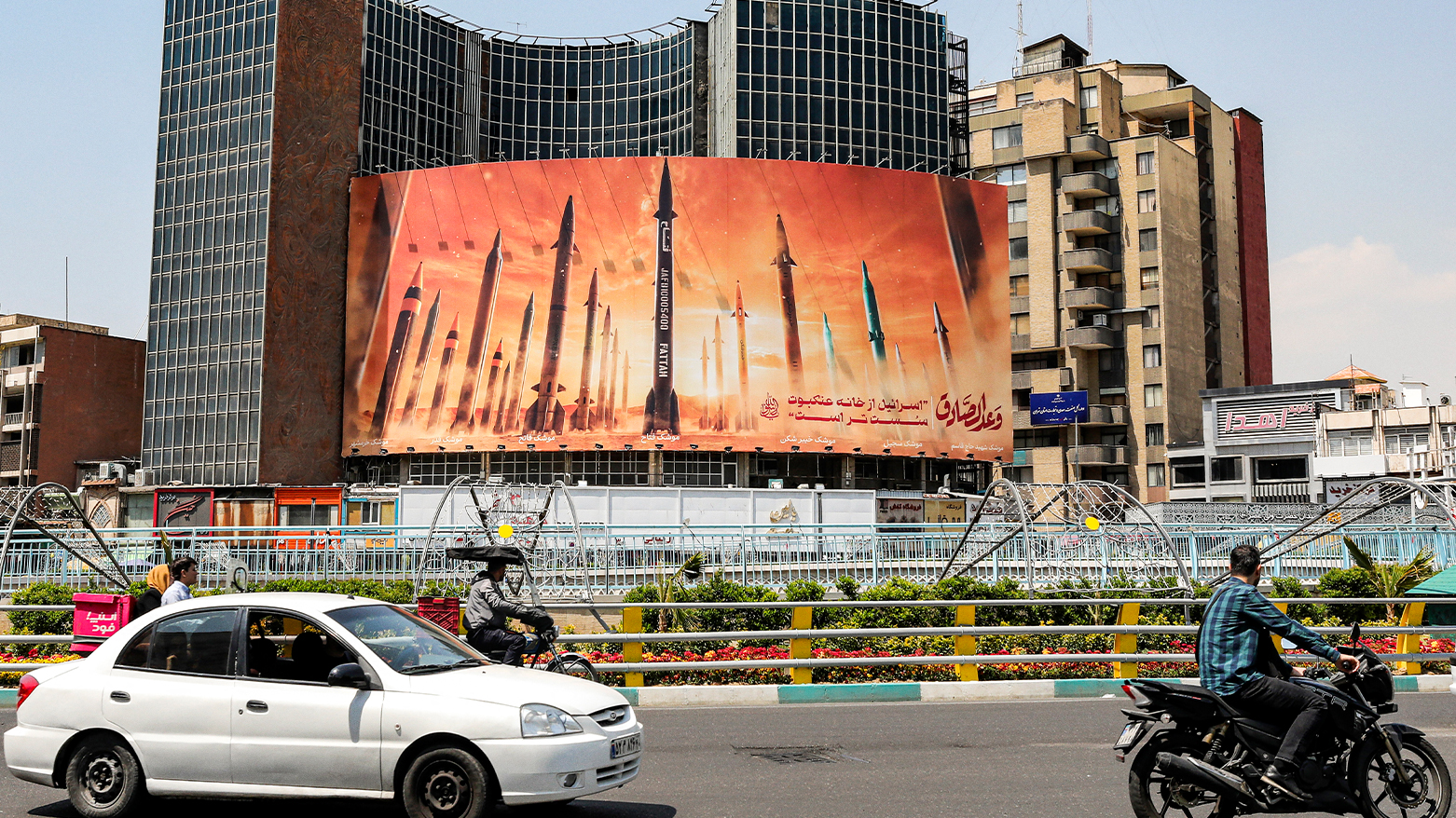 Motorists drive their vehicles past a billboard depicting named Iranian ballistic missiles in service. (Photo: AFP)