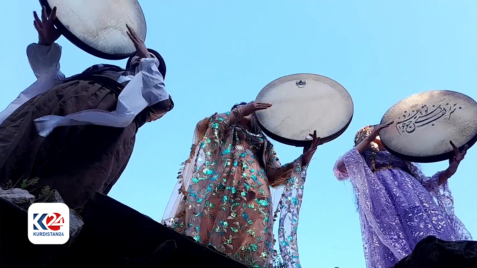 Kurdish male and females in traditional and colorful attire, playing daf during the festival.