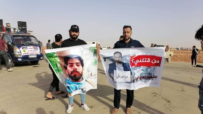 Qassim Bahloul al-Tamimi (Right), in Wasit protests holding a sign of assassinated activists Ihab al-Wazni with the question “Who Killed me.” (Photo: social media)