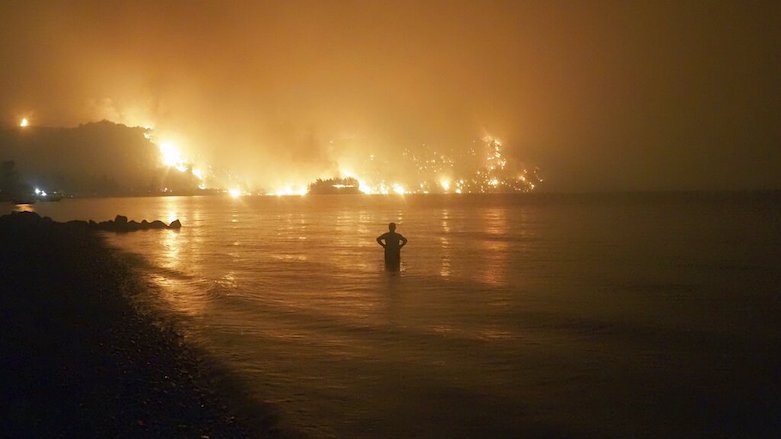 A man watches as wildfires approach Kochyli beach near Limni village on the island of Evia, about 160 km north of Athens, Greece, Aug. 6, 20021. (Photo: Thodoris Nikolaou/AP)