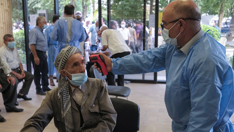 A medic checks an elderly man's temperature as he arrives to receive the Astrazeneca COVID-19 vaccine at an inoculation centre in Erbil,  August 7, 2021. (Photo: Safin Hamed/AFP)