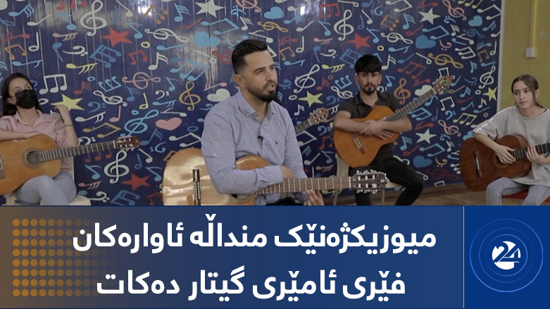میوزیکژەنێک منداڵە ئاوارەکان فێری ئامێری گیتار دەکات