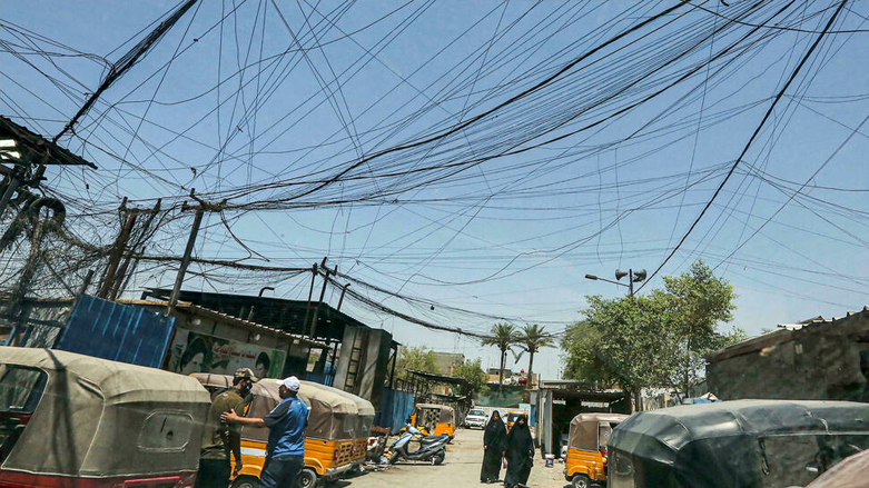 Iraqis walk under cables of private electric generator providers in Sadr City district, Baghdad, Iraq, July 16, 2021. (Photo: AFP)