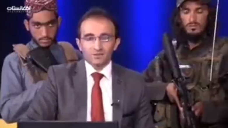 عناصر من طالبان مدججون بالسلاح خلف مذيع تلفزيوني