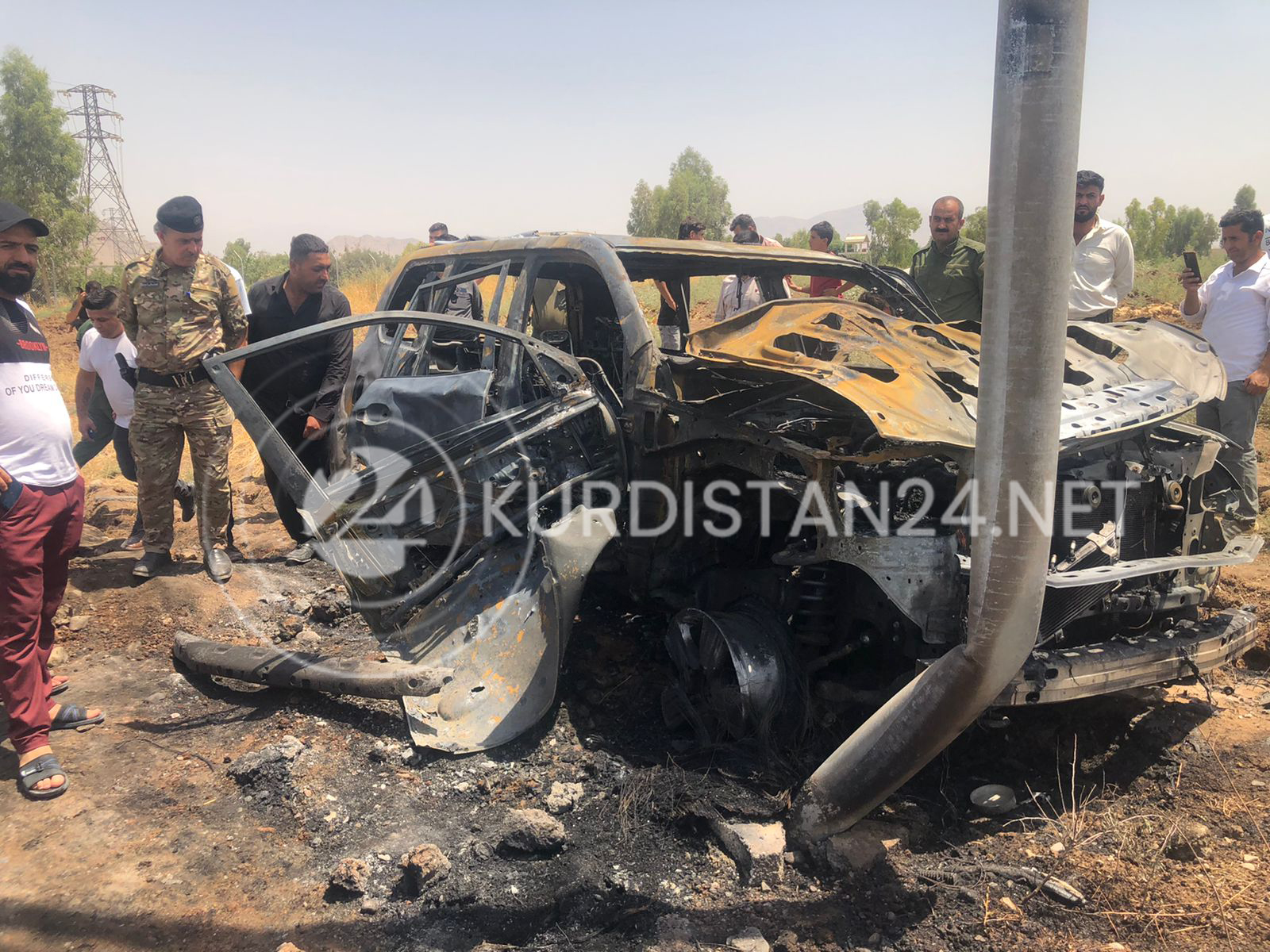 Security forces and onlookers at the site of the strike that destroyed the Toyota Land Cruiser, Aug. 1, 2022 (Photo: Aras Amin/Kurdistan 24)