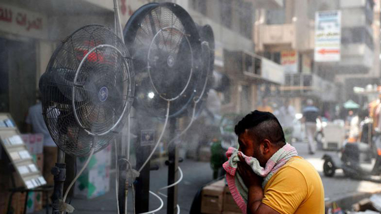A man stands by fans spraying air mixed with water vapour deployed by donors to cool down pedestrians along a street in Iraq's capital Baghdad, June 30, 2021. (Photo: Ahmad Al-Rubaye/AFP)