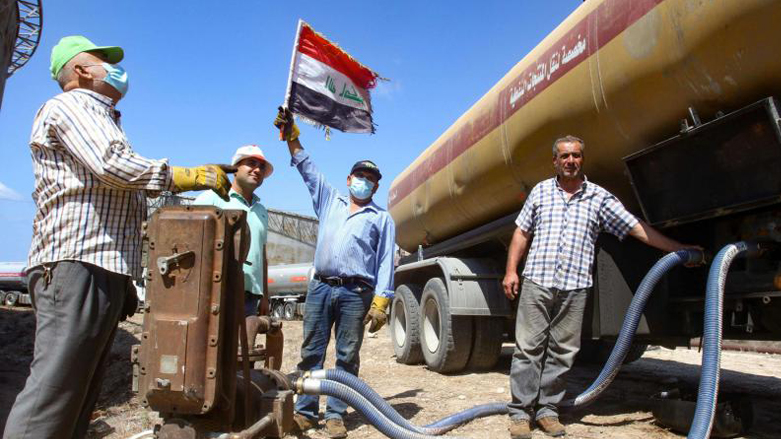 A worker raises an Iraqi flag as a fuel-loaded tanker is emptied of its content to a Lebanese refinery, August 20, 2020. (Photo: AFP)