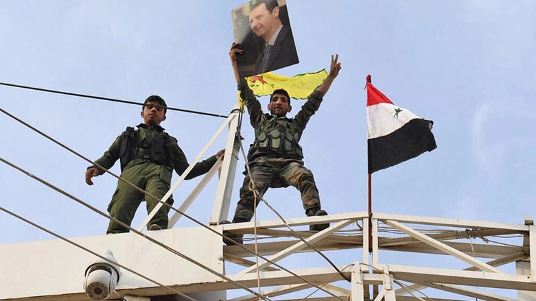 جندي سوري يرفع شارة النصر حاملا صورة للرئيس السوري بشار الأسد قرب مدينة كوباني في شمال سوريا في 19 تشرين الأول/أكتوبر 2019- الصورة لفرانس 24