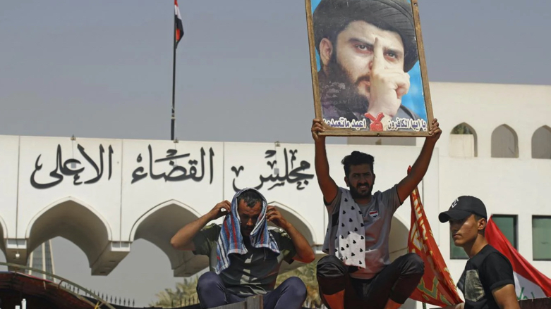 A supporter of Iraqi Shia cleric Moqtada al-Sadr raises his portrait during a protest outside the headquarters of the Supreme Judicial Council in Baghdad on 23 August 2022 (Photo: AFP).FP)