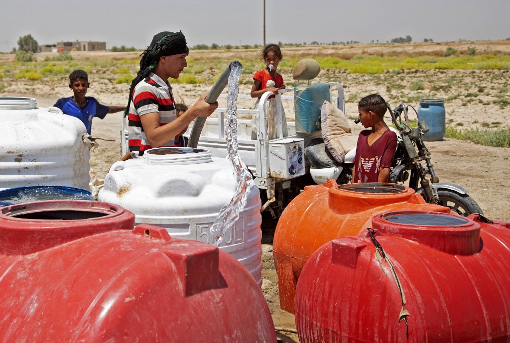 Children collect water from a cistern amid shortage and high temperature in the village of al-Aghawat in Iraq's central Diwaniya province, July 18, 2022. (Photo: Haidar Indhar/AFP)