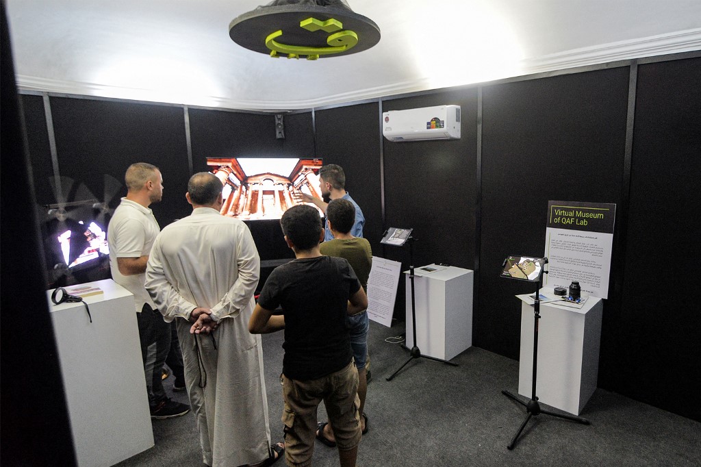 Ayoub Thanoon Younes (R behind), founder of the Mosul Heritage project, instructs visitors on the 3D technology used to view reconstructed models of ancient artefacts destroyed during the occupation of Mosul by Islamic State, August 3, 2022. (Photo: Zaid Al-Obeidi/AFP)