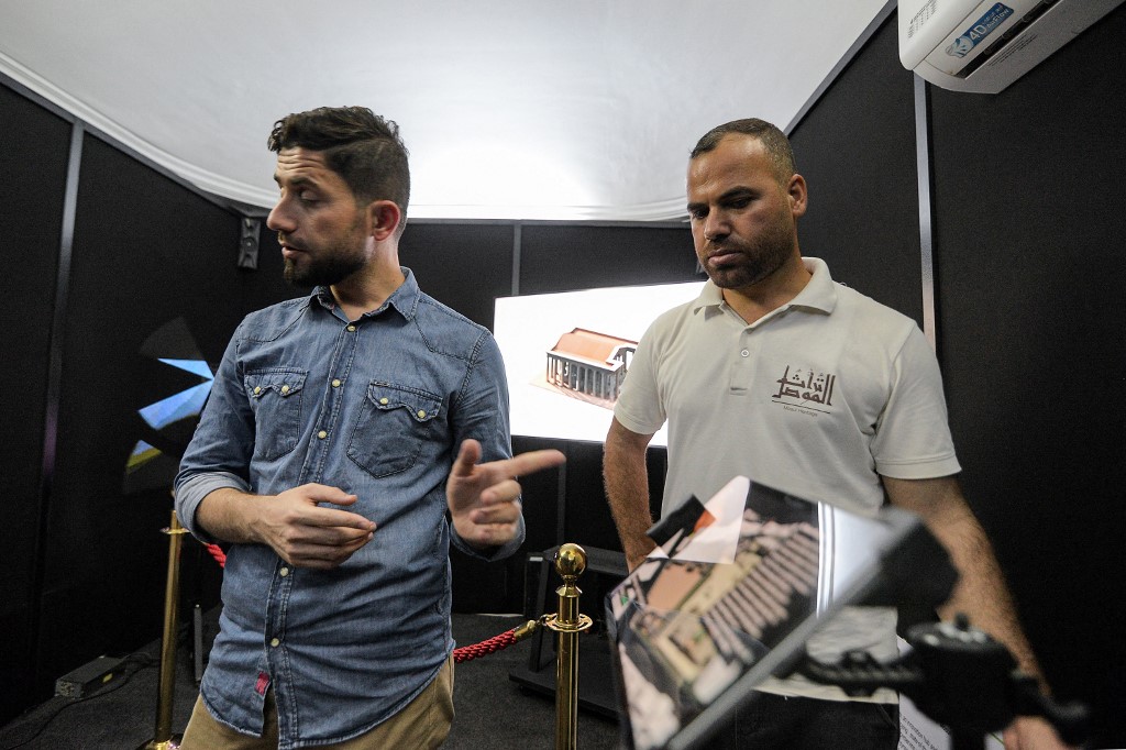 Ayoub Thanoon Younes (L), founder of the Mosul Heritage project, instructs visitors on the 3D technology used to view reconstructed models of ancient artefacts destroyed during the occupation of Mosul by Islamic State (IS), August 3, 2022. (Photo: Zaid Al-Obeidi/AFP)