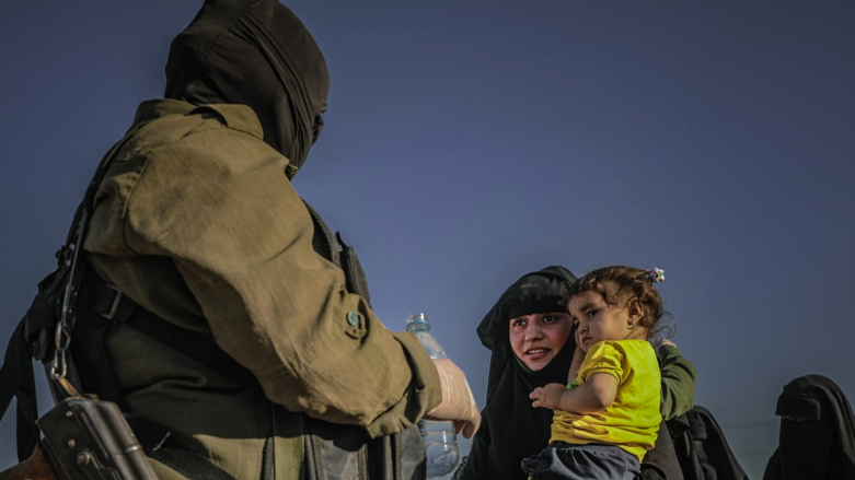 Asayish officer offers water to woman in al-Hol camp (Photo: Asayish).