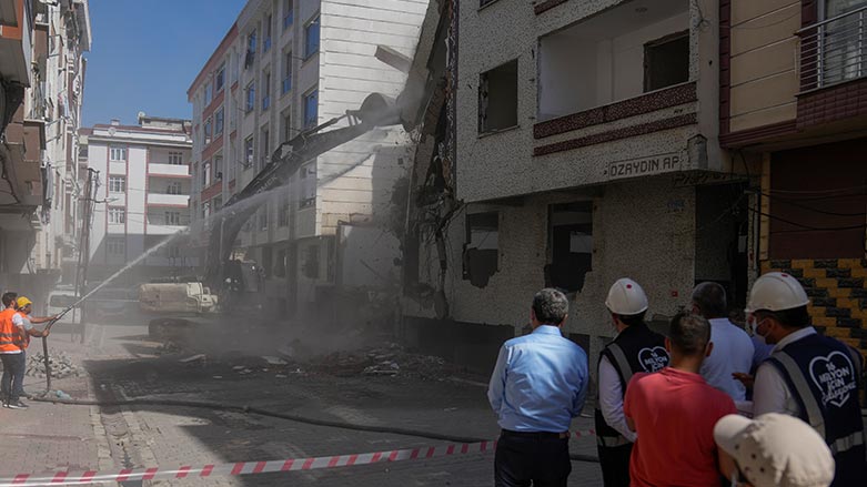 People on a side watch an excavator demolishing an old apartment building in Istanbul, Turkey, Friday, Aug. 4, 2023. (Photo: Khalil Hamra/ AP)