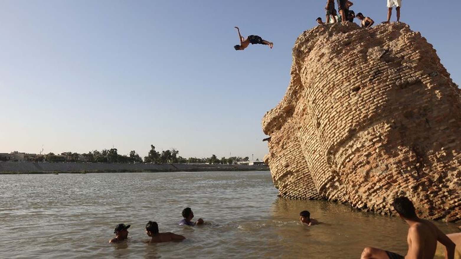 Tourists and residents dive into the Tigris River amid scorching summer heat. (Photo: Ahmad Al-Rubaye/AFP)