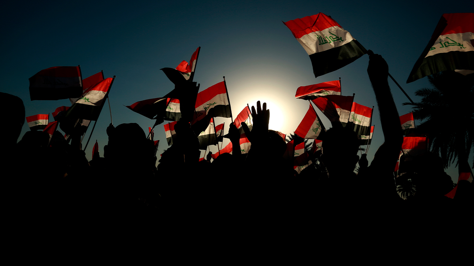 Iraqis holding and waving the flags of their country. (Photo: AP/Hadi Mizban)