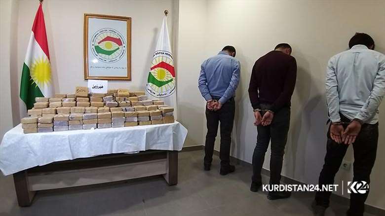 Three individuals facing drug charges stand next to a table displaying the contraband they are accused of possessing. (Photo: KRG)