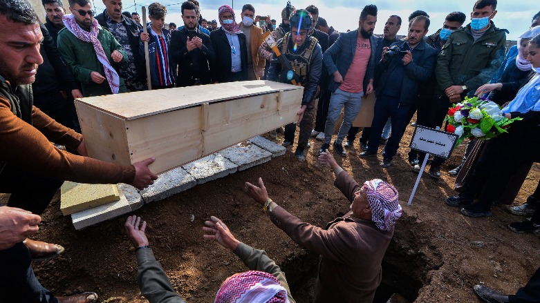 Mourners gather around as a coffin is buried a coffin during a a mass funeral for Yezidi (Ezidi) victims of ISIS in the disputed Iraqi district of Sinjar (Shingal), Feb. 6, 2021. (Photo: Zaid al-Obeidi/AFP)