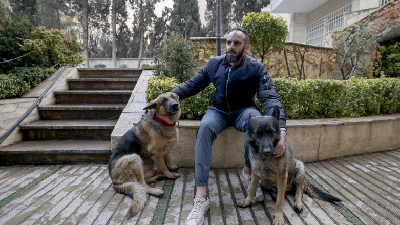 An Iranian man poses for a picture with his dogs in a yard near his house in northern Tehran, on December 5, 2021. (Photo: ATTA KENARE / AFP)