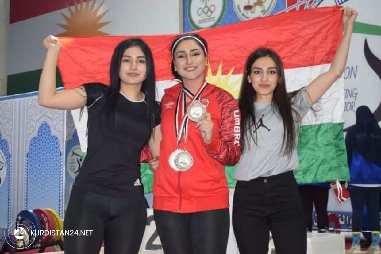 Три сестры держат флаг Курдистана после завоевания в общей сложности 12 золотых и серебряных медалей на чемпионате арабских стран по тяжелой атлетике, 29 декабря 2021 г. (Загрос Акбар/Курдистан 24)