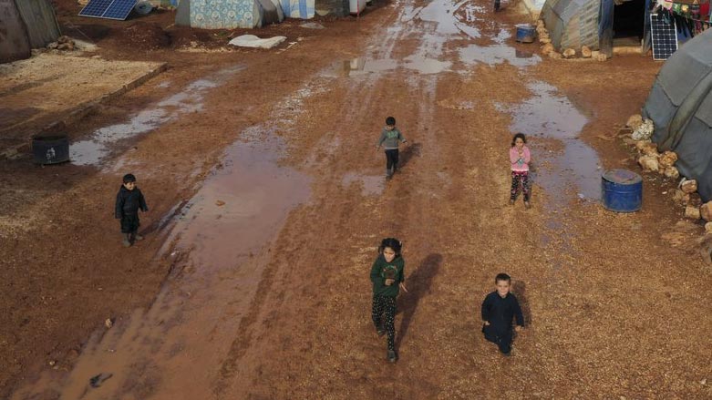Syrian refugees walk through a camp for displaced muddied by recent rains near the village of Kafr Aruq, in Idlib province, Syria. (Photo: AP/Ghaith Alsayed)