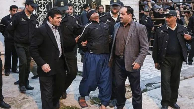 Blindfolded Iranian convicted man being escorted by officials and security to be prepared for his execution in public in the northern city of Nour, Iran. (Photo: AP)